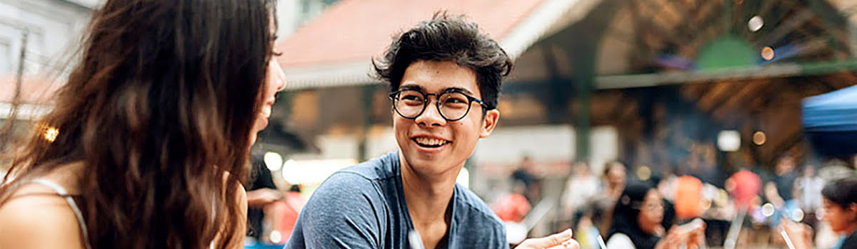 Young man with glasses laughing and enjoying dinner in Singapore