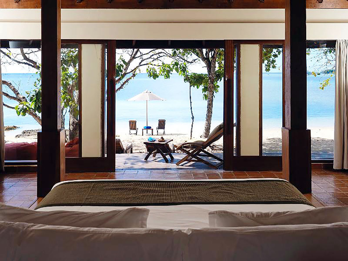 Scenic view of beach and ocean from king-size bed in room at Menjangan Resort